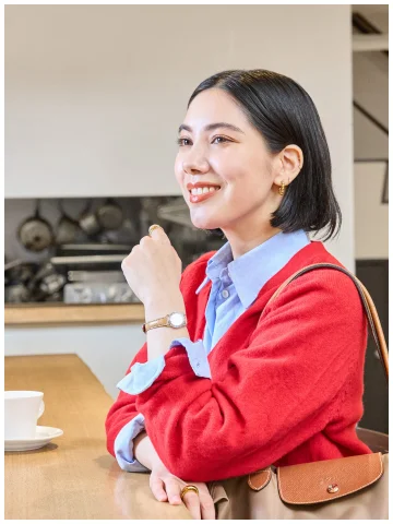 赤いカーディガンを着て時計ベルトを身につけた女性