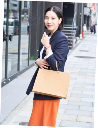 紙袋を手に街を歩く女性